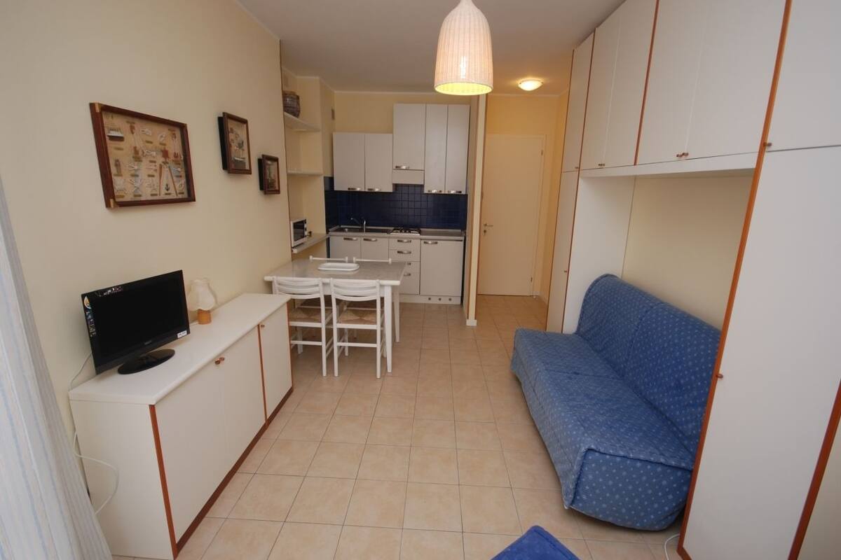 Ein kompakter Wohnbereich mit Küchenzeile, Essbereich, einer Couch und einem Fernseher.