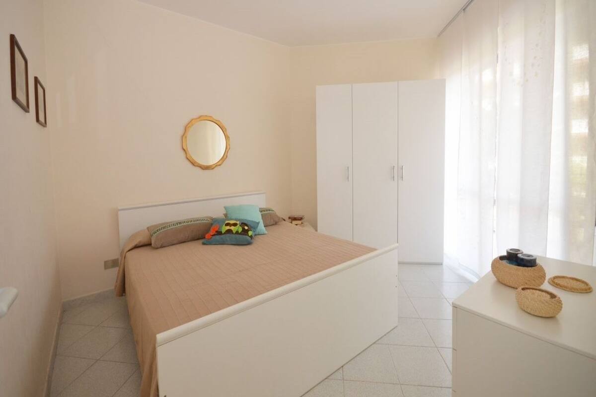 Ein Schlafzimmer mit Bett, Nachttisch, Kleiderschrank und einem Fenster mit Vorhängen.