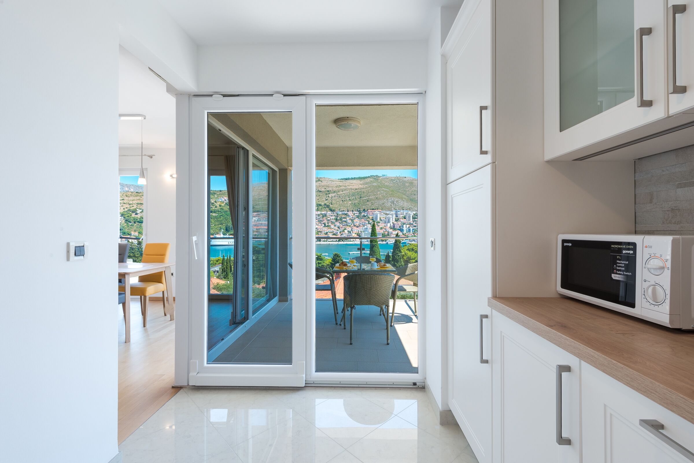 A modern kitchen with a view of a balcony and cityscape.