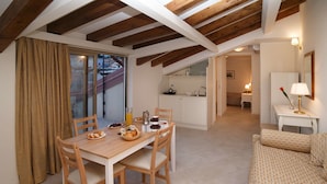 A dining area with a wooden table and chairs, a kitchen in the background, and a cozy living space with a patterned sofa. - Marina Di Savoca (Santa Teresa di Riva)