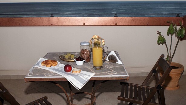 A table with breakfast items, a view of the ocean, and a potted plant. - Marina Di Savoca (Santa Teresa di Riva)