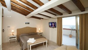 A bedroom with a bed, bedside tables, a TV, and a balcony with a view. - Marina Di Savoca (Santa Teresa di Riva)
