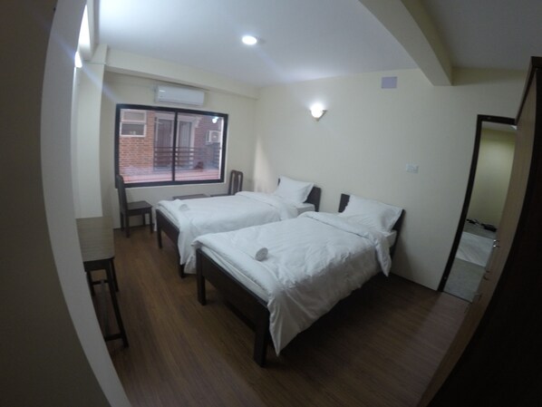 A room with two beds, a window, and a door.