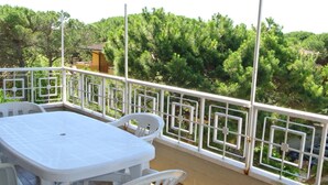A balcony with a white table and chairs, surrounded by a white railing with geometric patterns. - Residence Gardenia (Lignano Sabbiadoro)