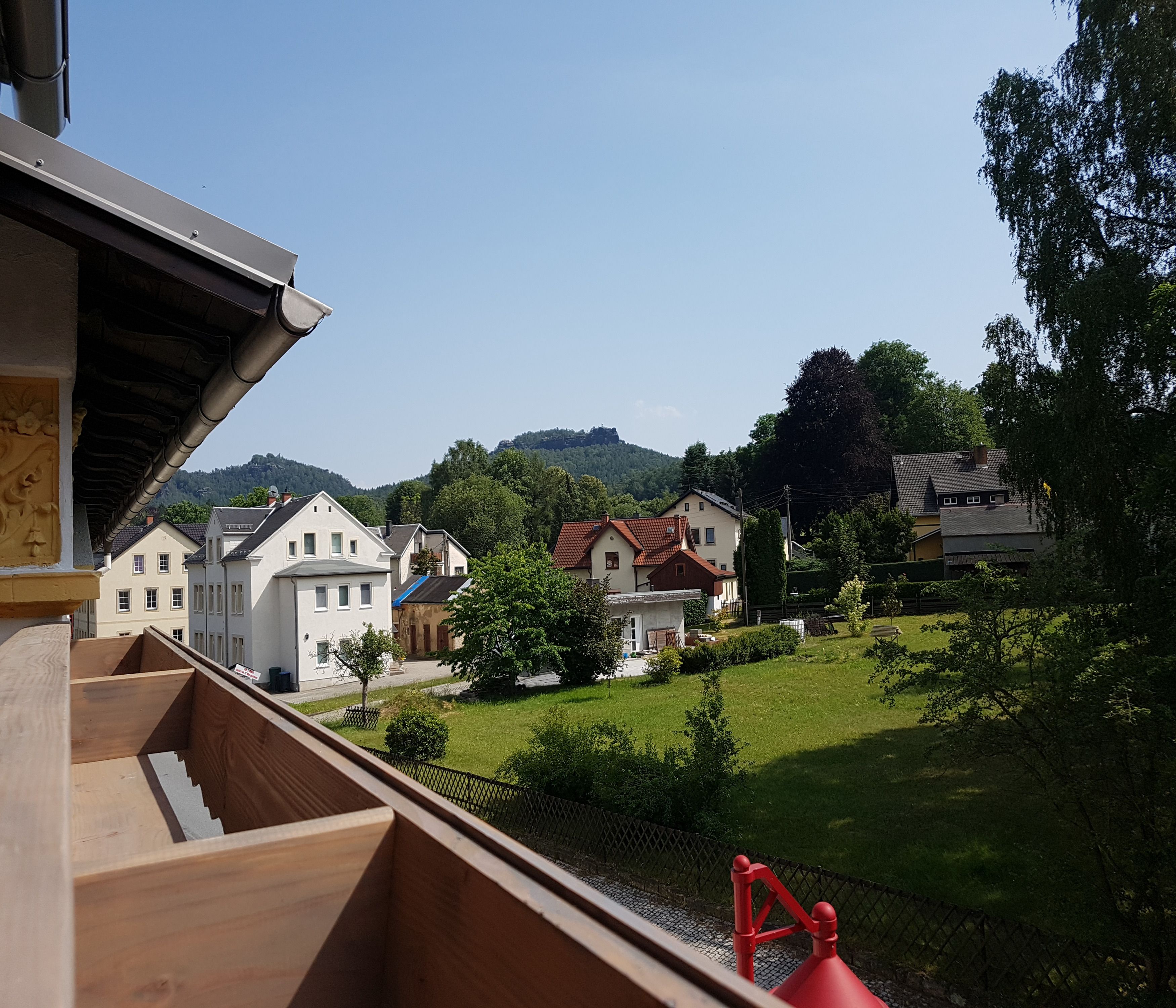 A residential area with houses, a grassy field, and a hill in the background.
