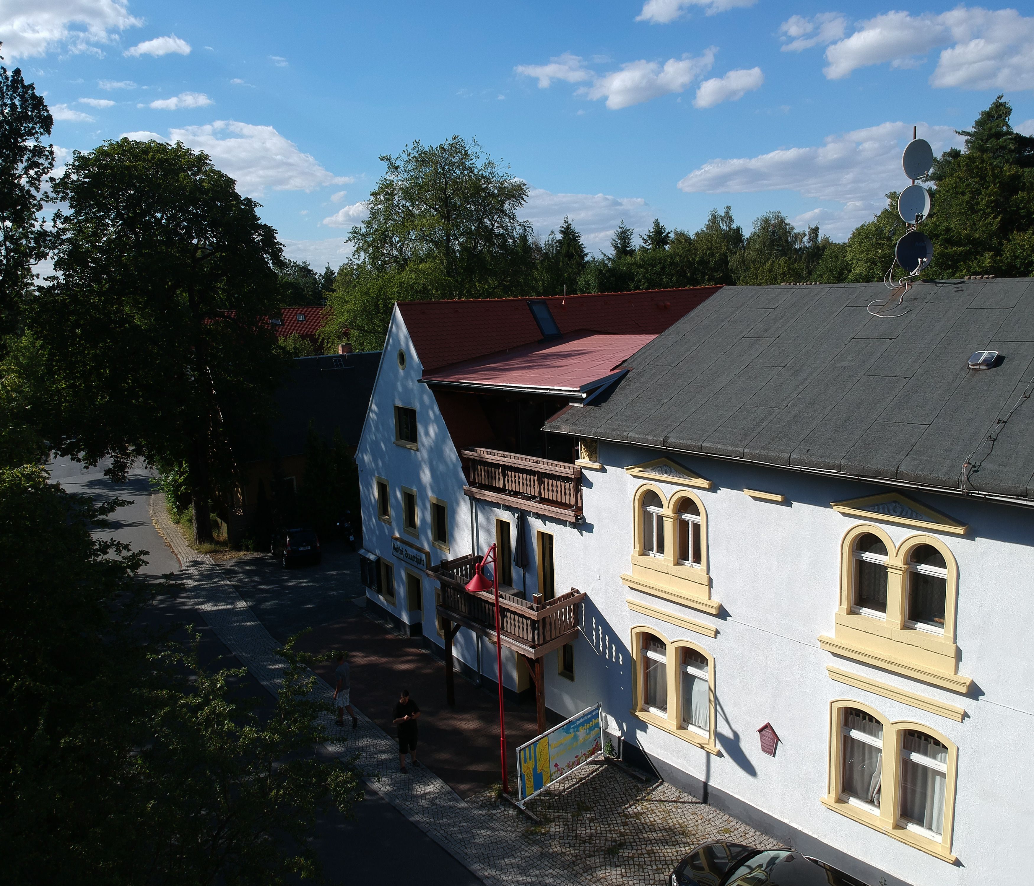 A traditional European building with a sloped roof, a balcony, and a cobblestone street.