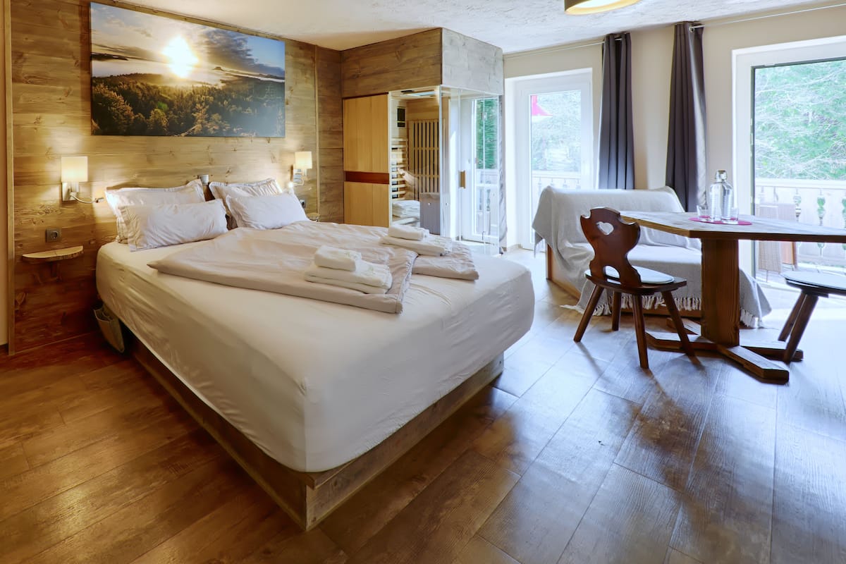 A hotel room with a large bed, a wooden headboard, a painting, a desk, and a chair.