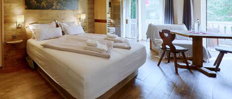 A hotel room with a large bed, a wooden headboard, a painting, a desk, and a chair.