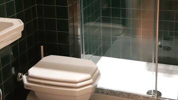 Un baño con inodoro, lavabo y zona de ducha.