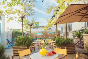 An outdoor patio area with round tables, yellow chairs, and potted plants. - Ostello Tasso (Florence)
