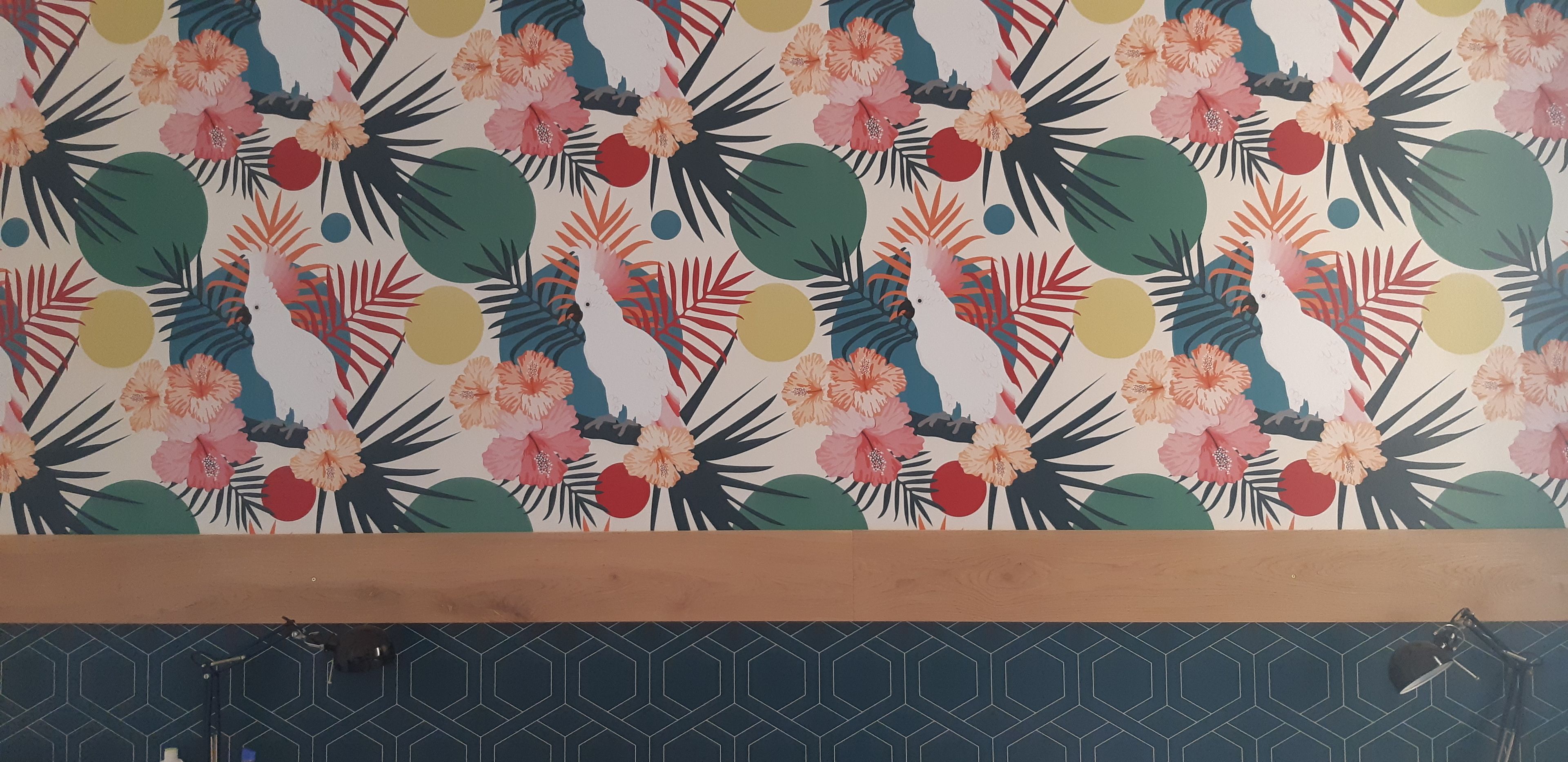 A room with a floral wallpaper, a wooden ceiling, and a geometric tile pattern on the lower wall.