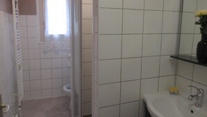Een badkamer met toilet, wastafel en douche.