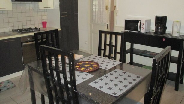 Een keuken met een eettafel, stoelen, een klok en een magnetron.