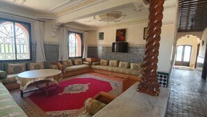 Un salon spacieux avec un grand canapé, une table basse ronde et un tapis rouge.