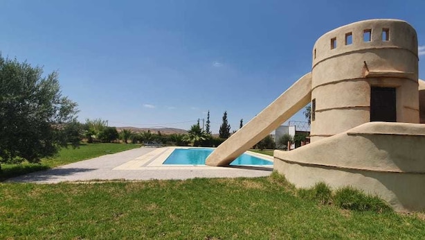 Une piscine dotée d’une structure architecturale originale, caractérisée par un design incurvé et une petite fenêtre.