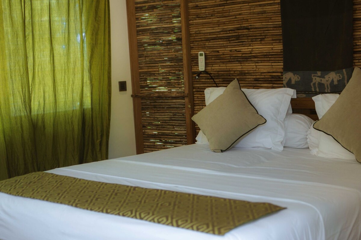 A hotel room with a bed, a control panel, and a decorative wall.