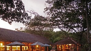 An outdoor dining area with wicker furniture and thatched-roof structures.