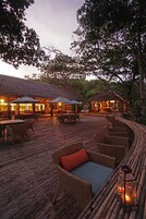 Un área de comedor al aire libre con mobiliario de mimbre y construcciones de techo de paja.