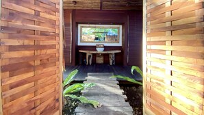 A wooden interior with a central seating area and a window overlooking a garden.