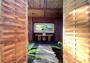Interior de madera con zona de estar central y ventana con vistas a un jardín.