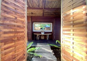 Interior de madera con zona de estar central y ventana con vistas a un jardín.