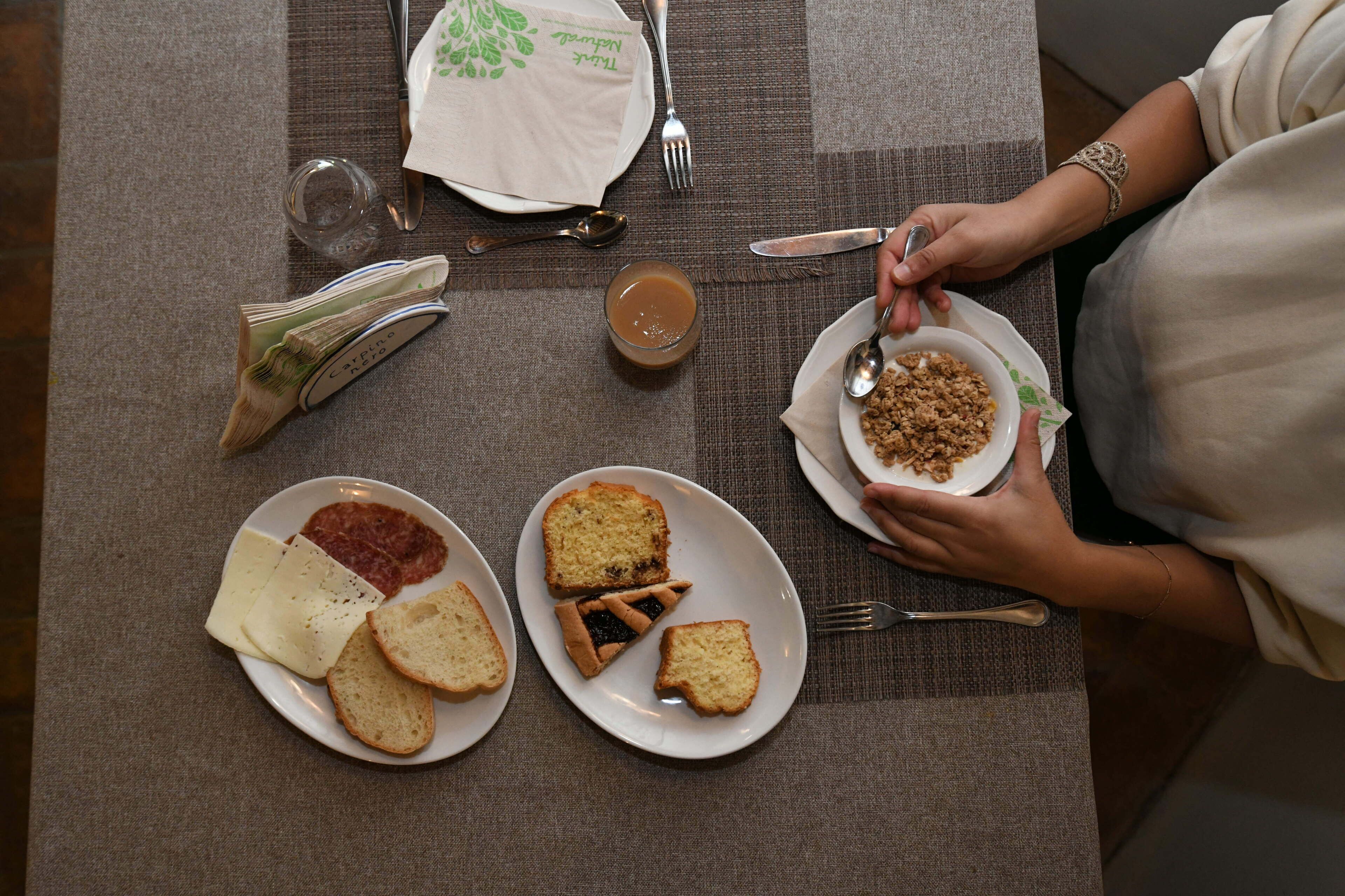 A table with plates of food, utensils, and a napkin with a green design.