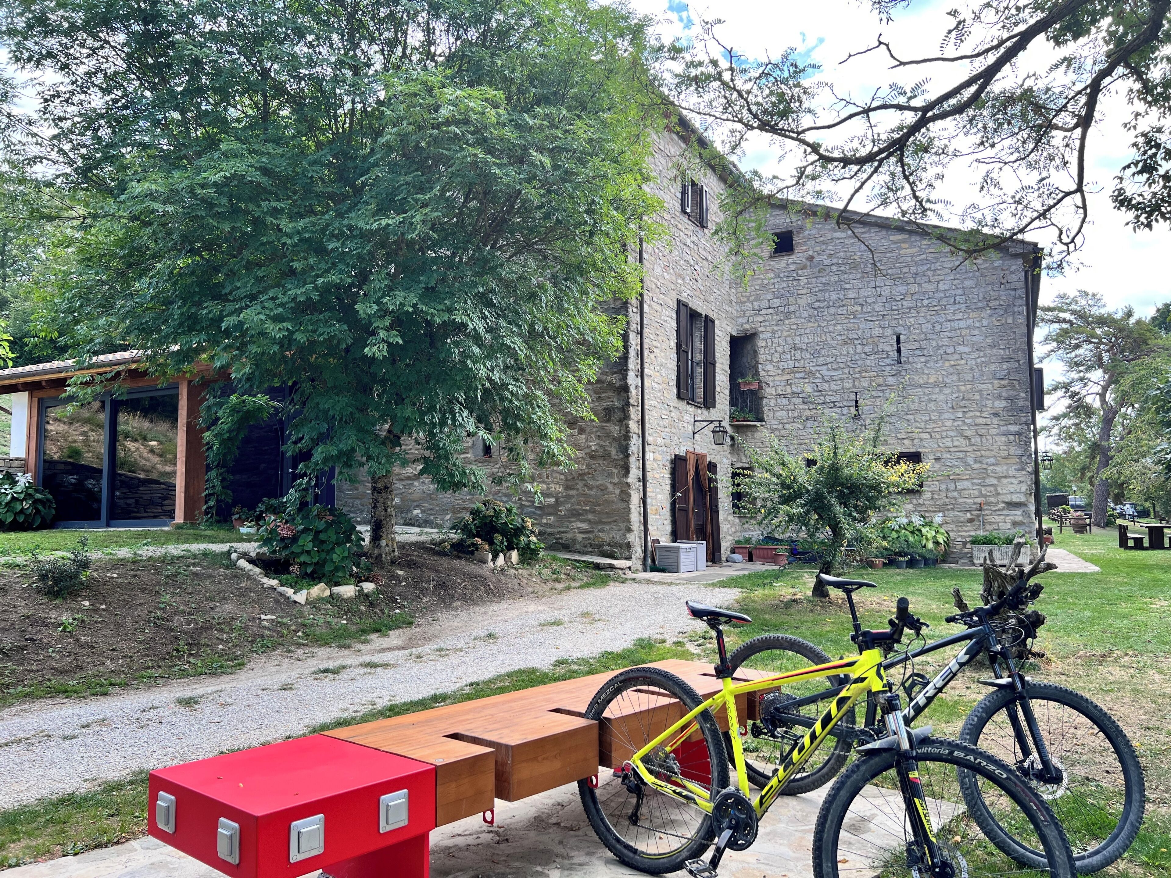 A stone building with a wooden bench and two bicycles.