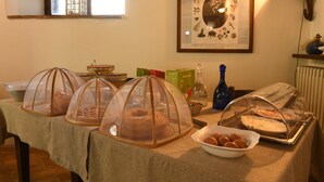 A table with covered food items, a framed picture on the wall, and a window with a view.