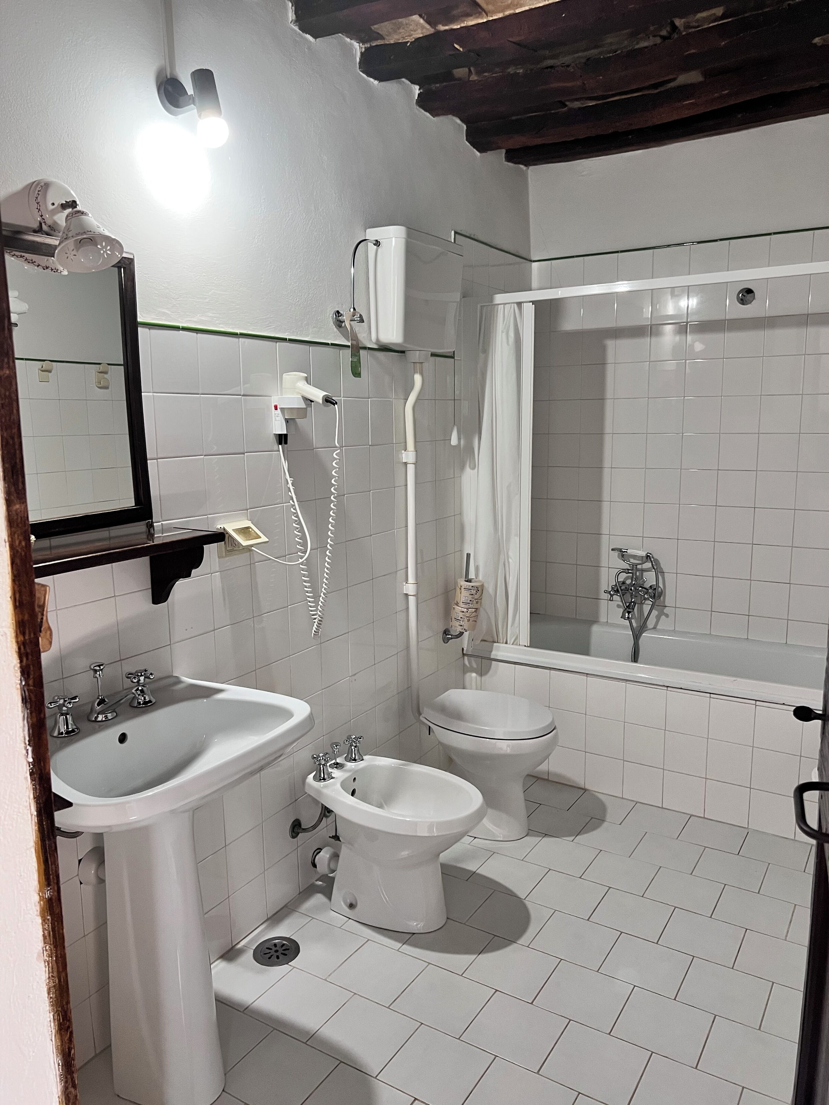 A bathroom with a sink, bidet, toilet, and bathtub.