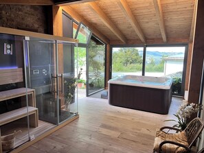 Une salle de bain moderne dotée d’une douche à parois de verre, d’un banc en bois, d’un jacuzzi et offrant une vue sur l’extérieur.
