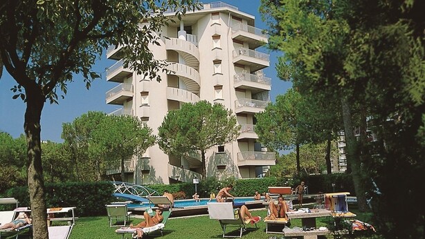 A multi-story building with balconies, a swimming pool, and outdoor seating areas.