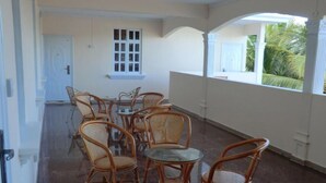 Una habitación con una mesa de vidrio rodeada de sillas de mimbre, una puerta blanca y una ventana con vistas a la vegetación.