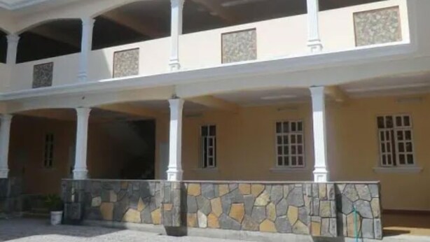 Un edificio de varios pisos con un patio central, columnas y un muro de piedra.