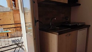 A compact kitchen with wooden cabinets, a black countertop, and a built-in microwave. - B&B Home Visit (Agrigento)