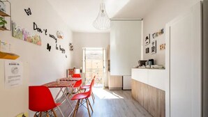 A modern kitchen with a wooden countertop, a dining area with red chairs, and a bright pendant light. - B&B Home Visit (Agrigento)