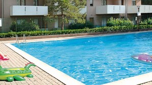 A swimming pool with a clear blue water surface, surrounded by a tiled deck. - Residence Orsa Maggiore (Lignano Sabbiadoro)