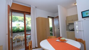 A dining area with a table, chairs, and a television mounted on the wall. - Residence Orsa Maggiore (Lignano Sabbiadoro)