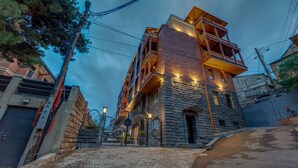 A multi-story building with a stone facade, a wooden balcony, and a sign indicating a sale. - Sole Palace (Tbilisi)