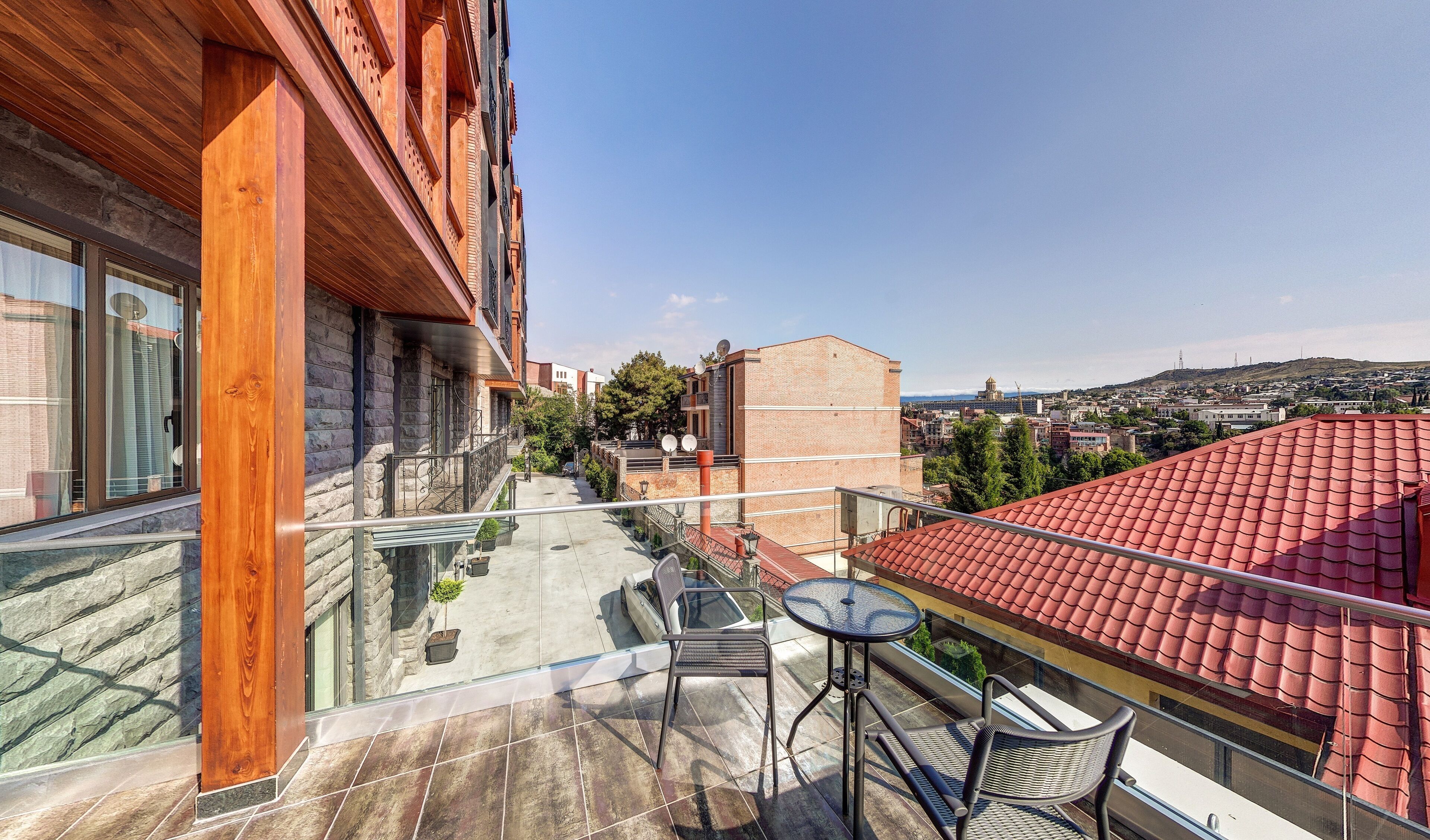 A balcony with a glass railing, a small table, and two chairs.