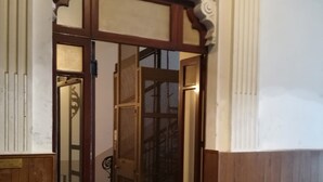 Una entrada con puerta de madera y panel de vidrio, que da paso a un interior con suelo de baldosas.