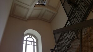 Una escalera con barandilla de hierro forjado y un amplio ventanal de arco.