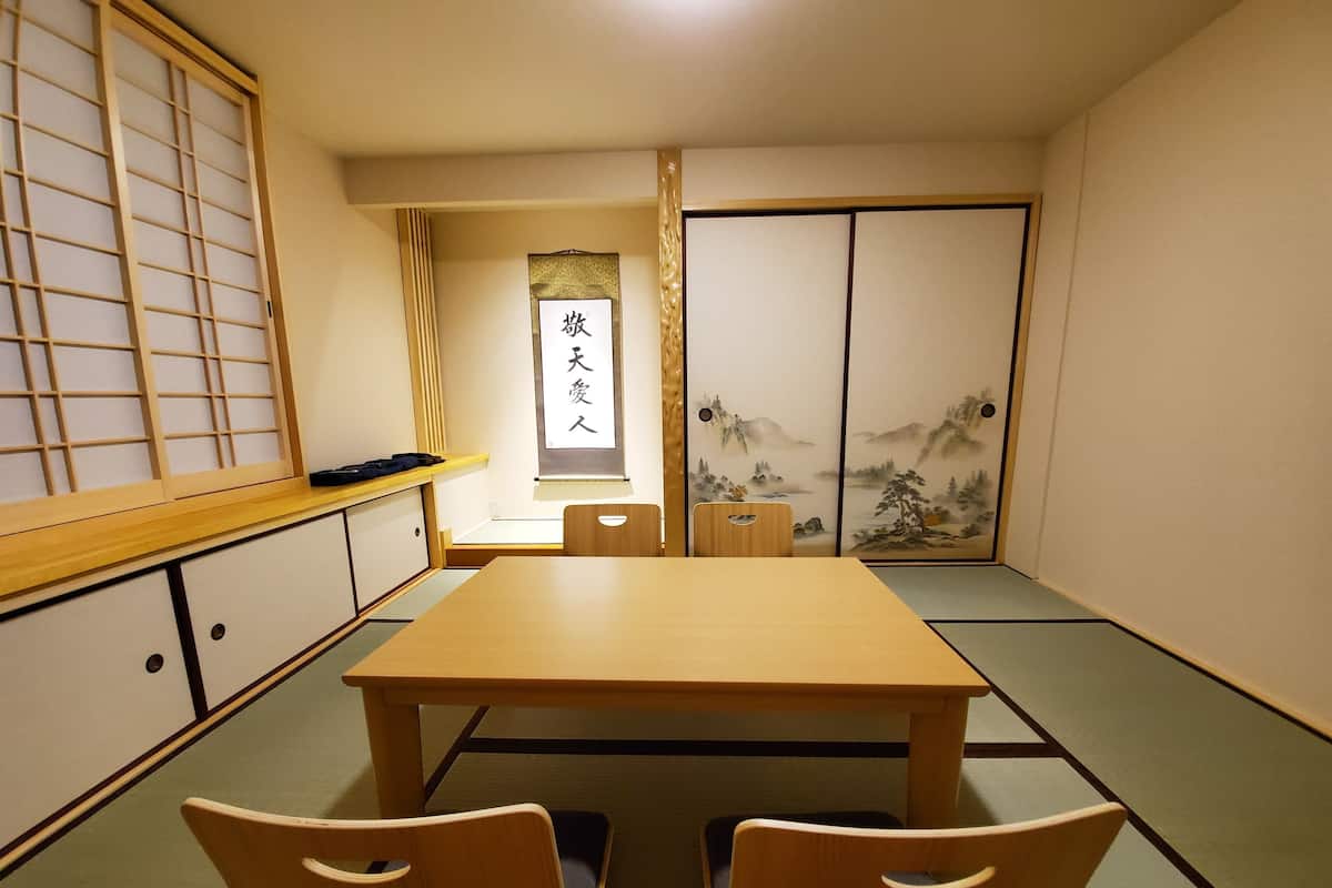 Um quarto japonês tradicional com tatames, uma mesa baixa e biombos shoji.