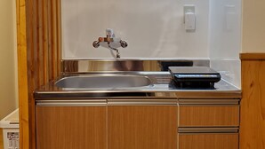A compact kitchen with a microwave, sink, and a scale on the countertop. - Sakuranomiya Hotel-Self Service (Osaka)