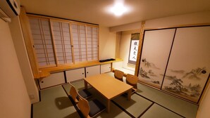 A traditional Japanese room with tatami flooring, a low table with four chairs, a sliding door with a landscape painting, and a shoji screen with a grid pattern. - Sakuranomiya Hotel-Self Service (Osaka)