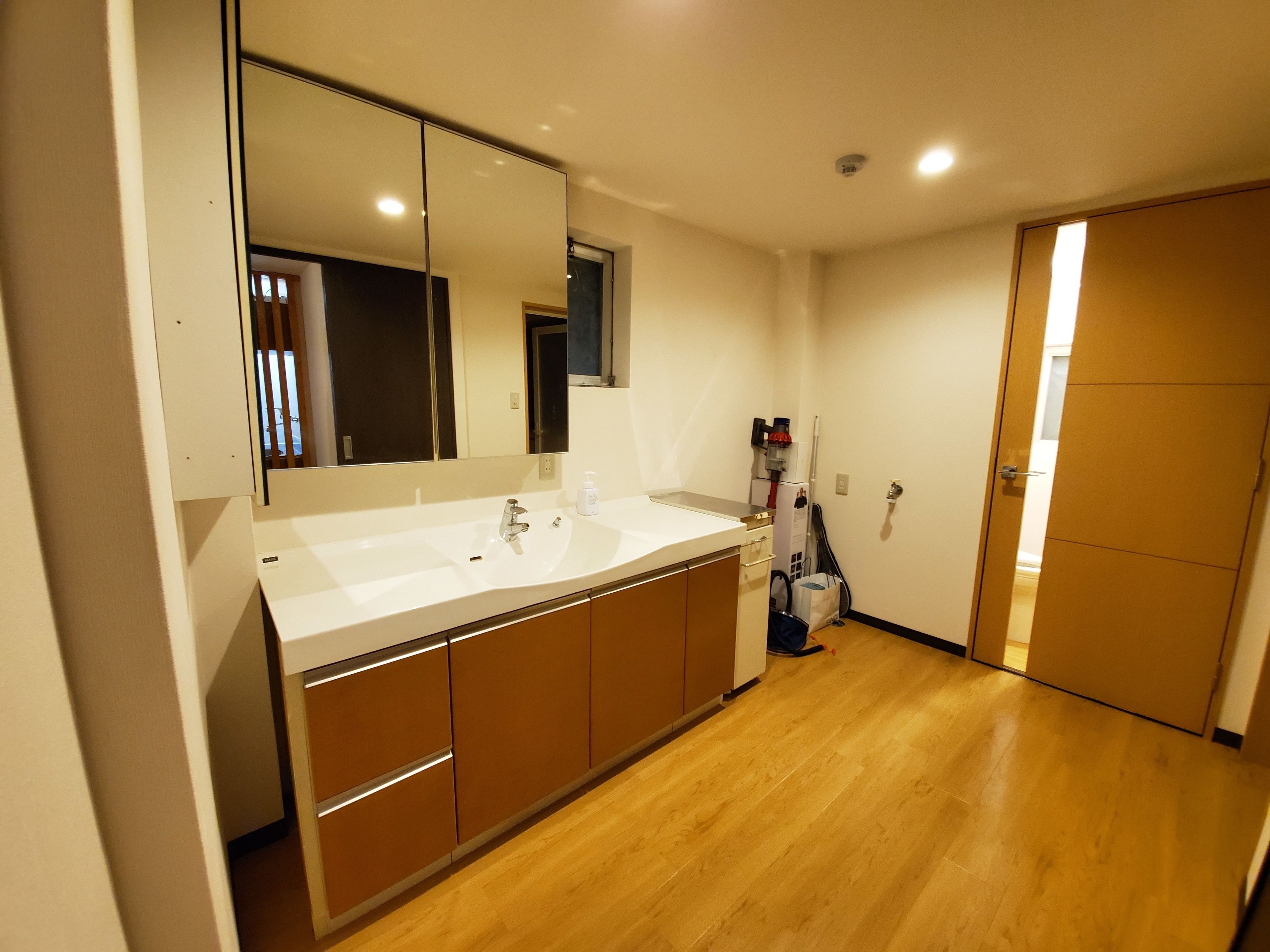 A modern bathroom with a large mirror, a sink, and wooden cabinets.