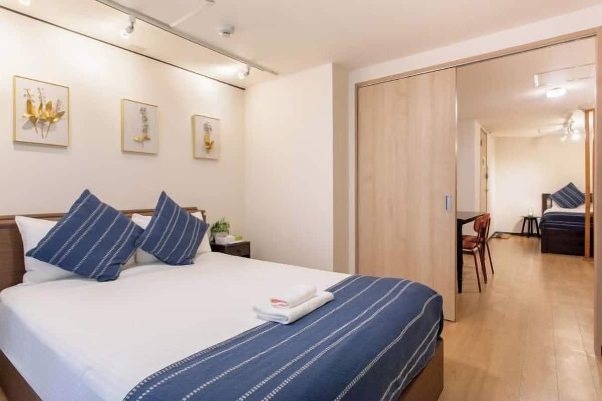 Quarto de hotel com uma cama, uma escrivaninha e uma cadeira.