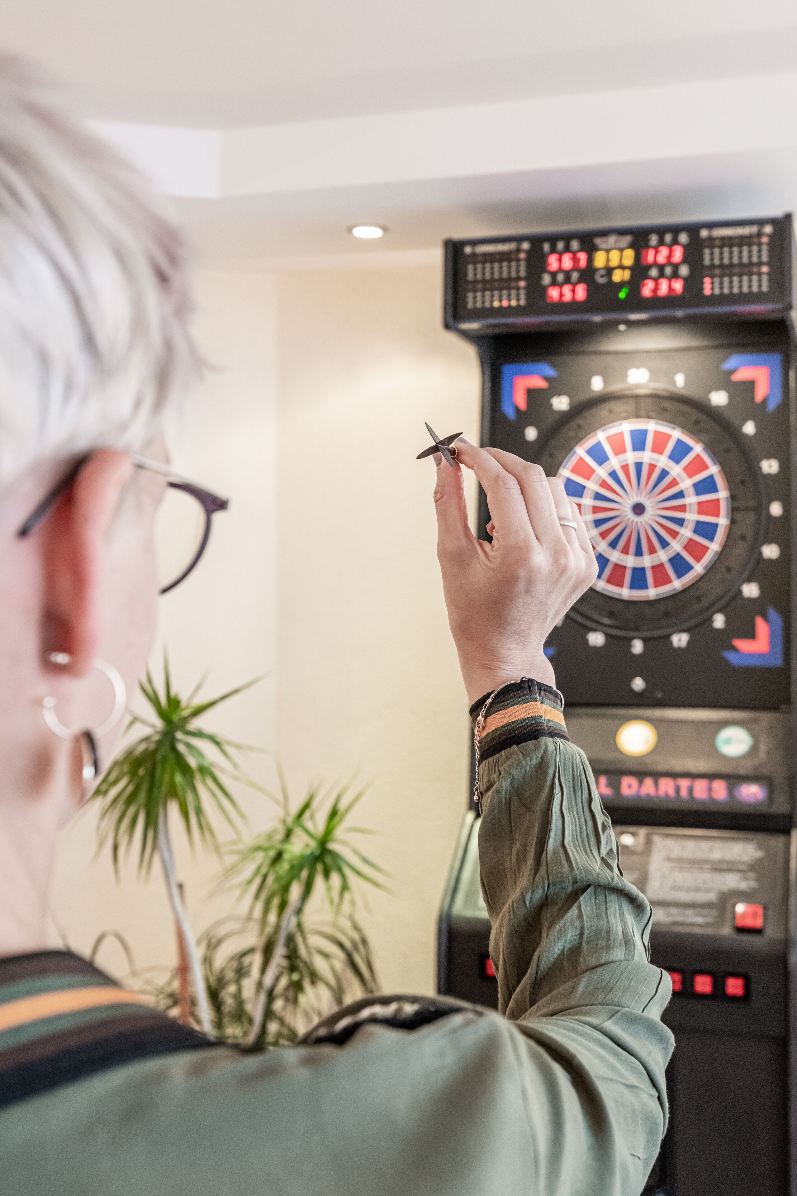 A dartboard with a score display and a dart in hand.