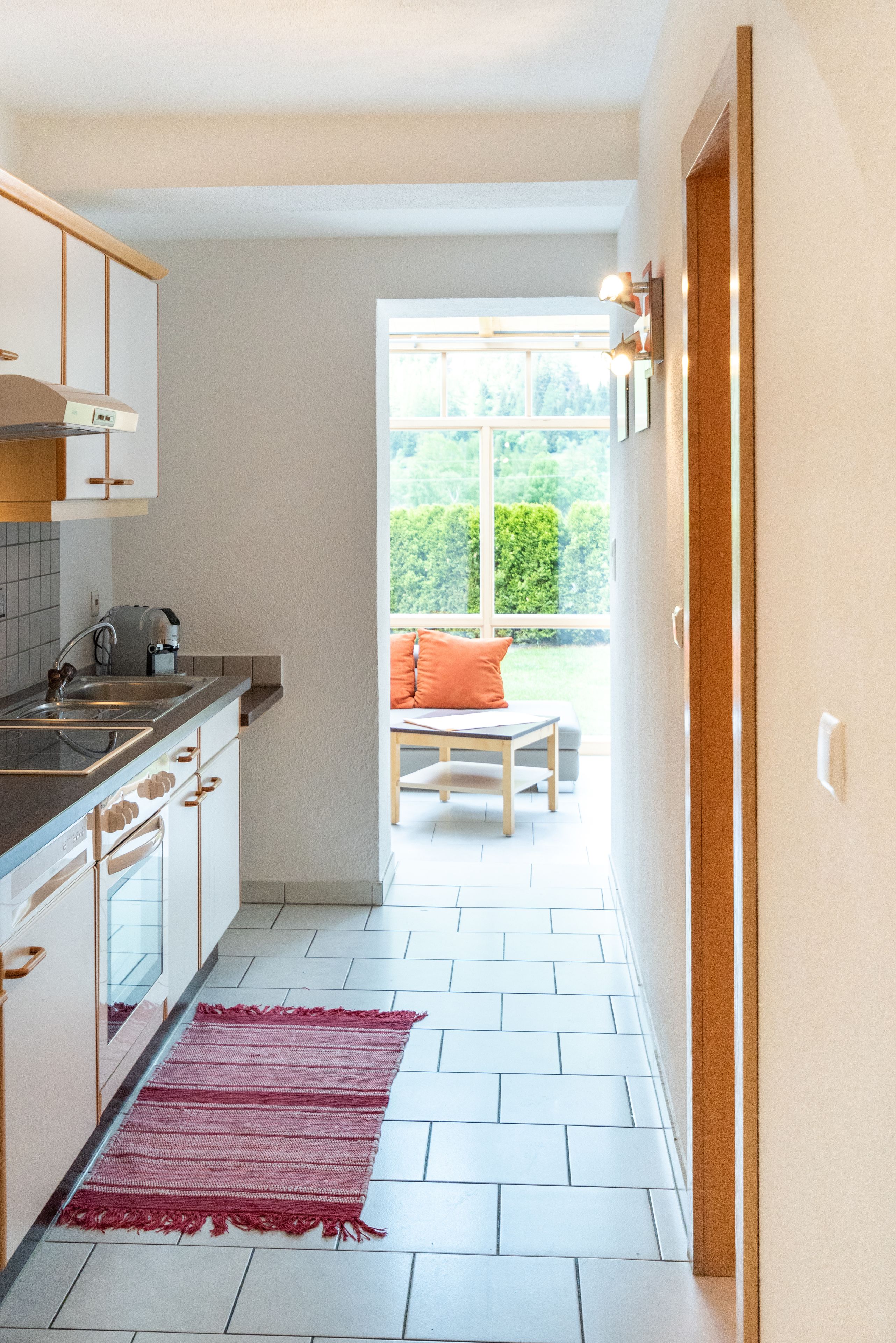A kitchen with a window leading to a balcony.