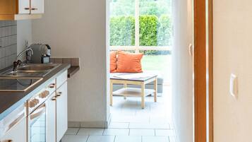 A kitchen with a window leading to a balcony.