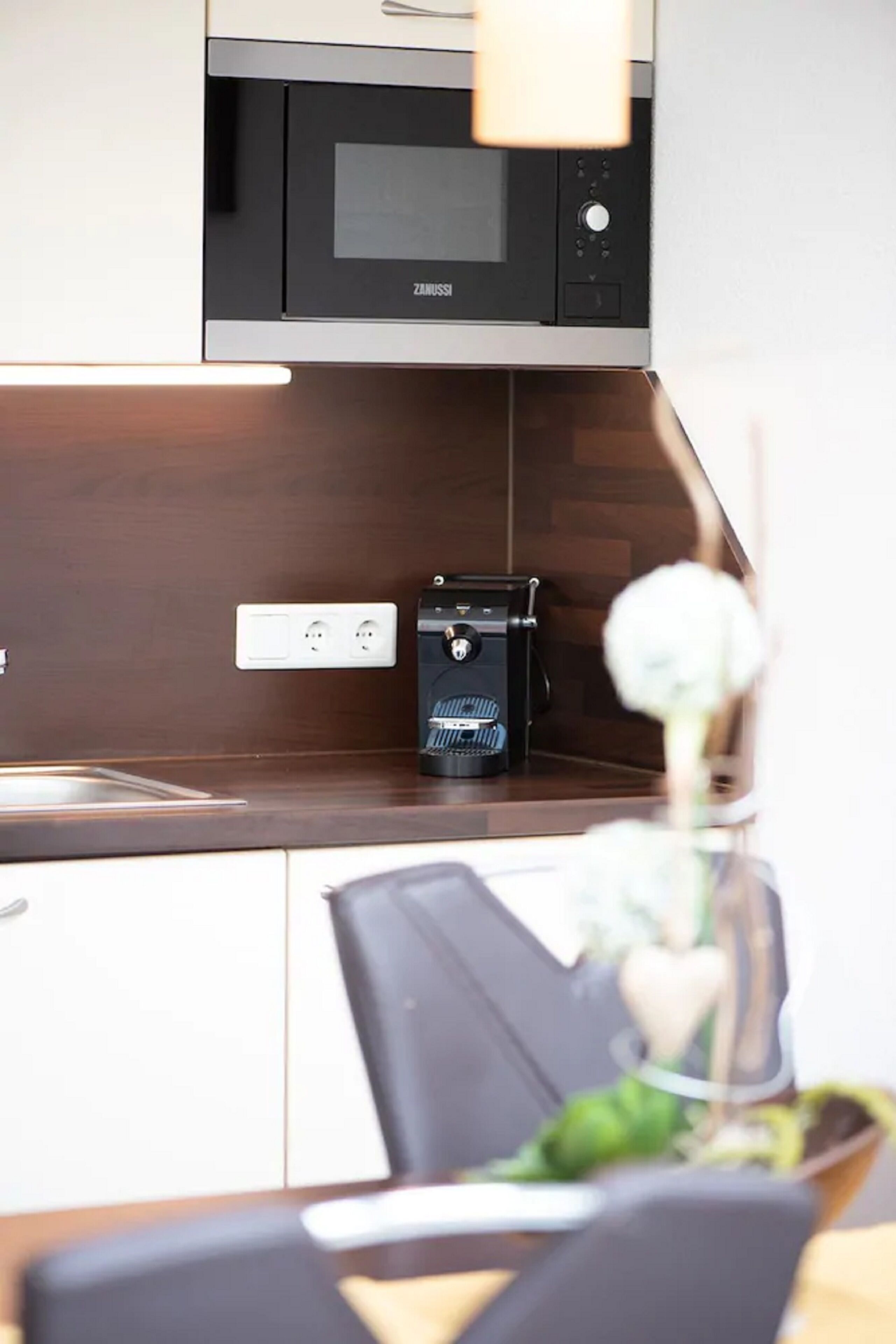 A modern kitchen with a built-in microwave, a coffee machine, and a wooden countertop.